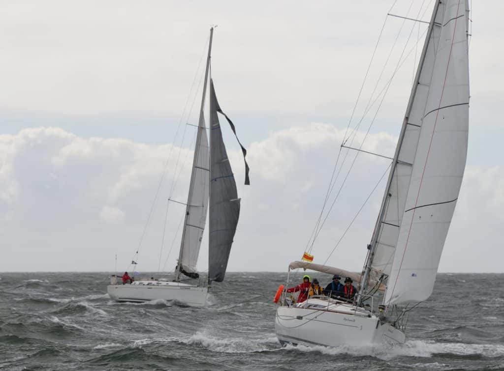 Two racing yachts, one with its genoa blown apart and flapping loose while sailing upwind