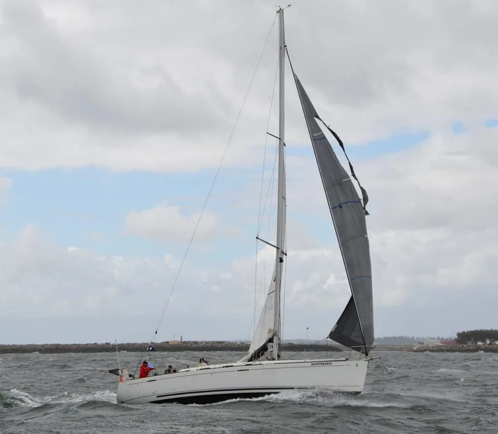 Sailboat close-hauled with its genoa torn apart along a seam and flapping in heavy wind
