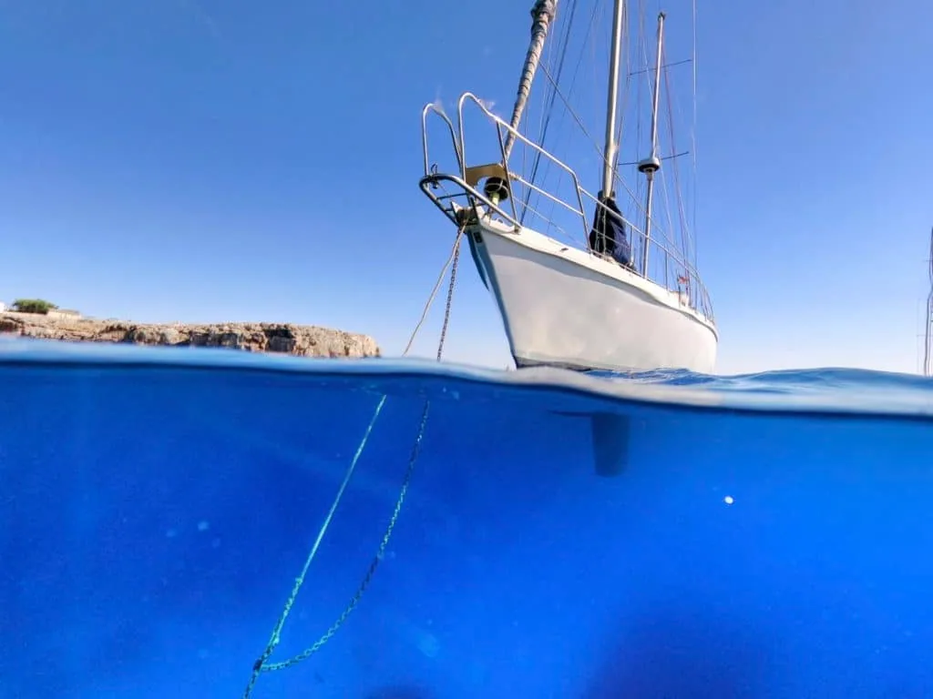 Sailboat's bow anchor rode with a rope snubber, shown split above and below the waterline