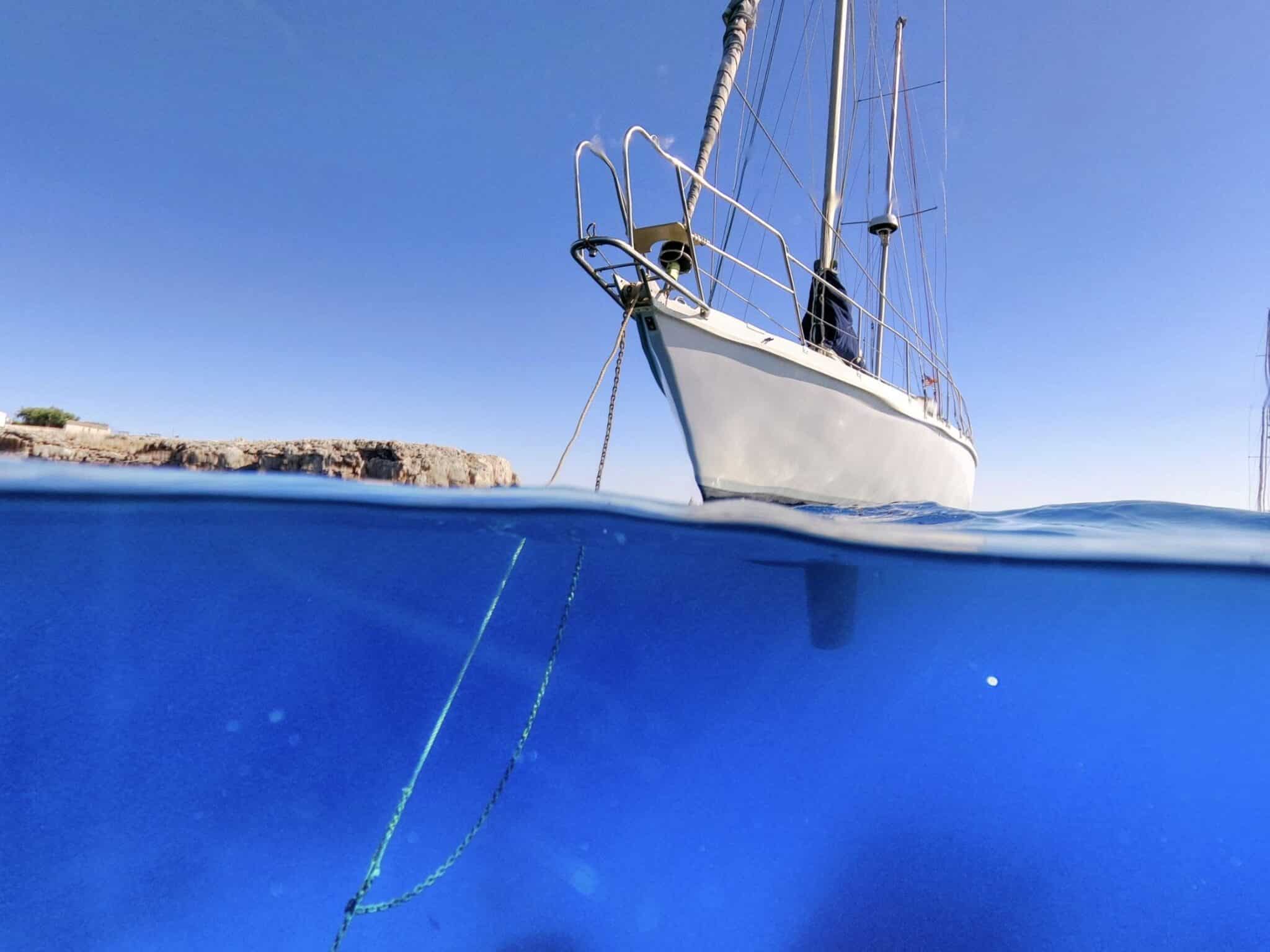 Sailboat's bow anchor rode with a rope snubber, shown split above and below the waterline