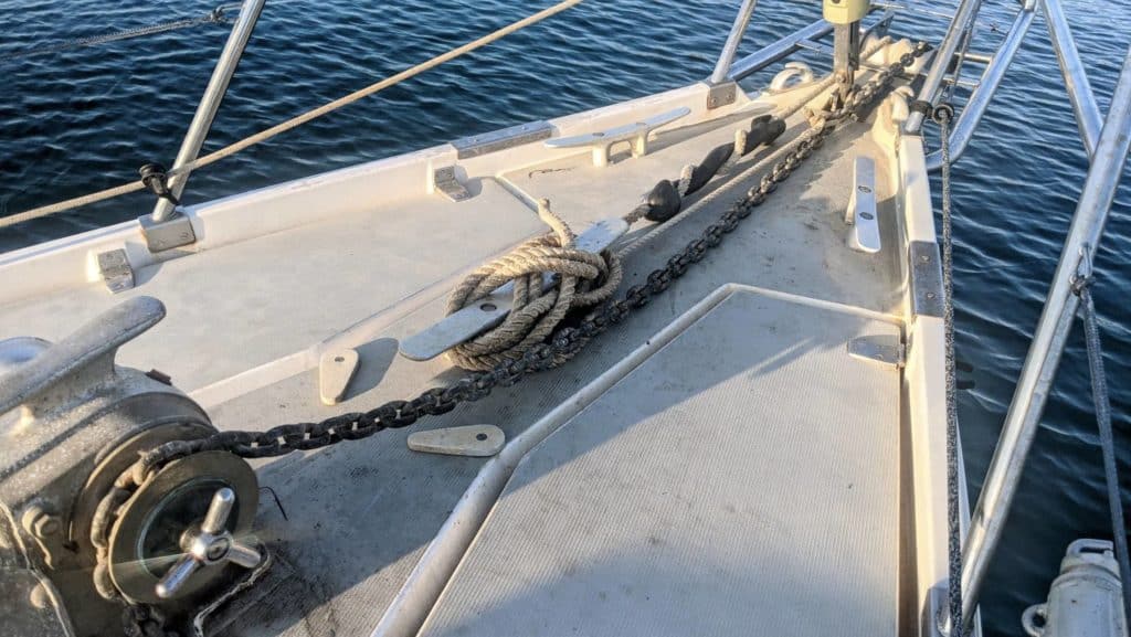 Anchor chain and rope snubber line cleated on a sailboat's foredeck