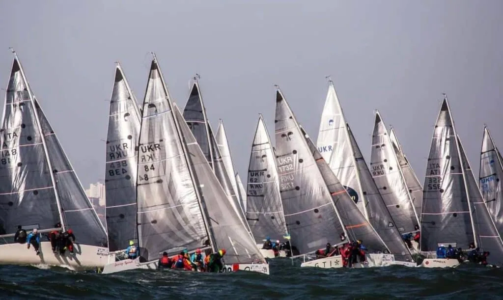 Large Platu 25 fleet racing upwind with overlapping grey sails at a championship start