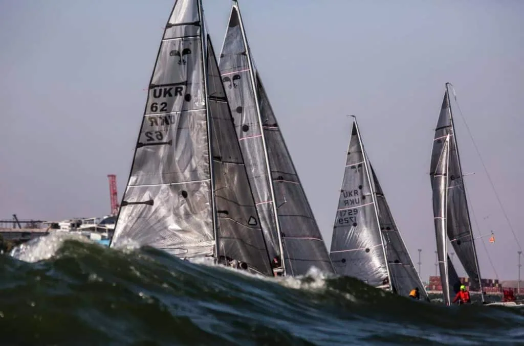 Platu 25 fleet led by sail number UKR 62 crashing through waves upwind in heavy air