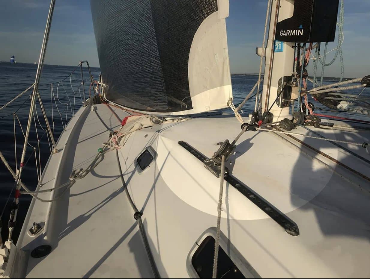 On-deck view of a bow with genoa sheeted in, showing blocks and tracks near the headstay