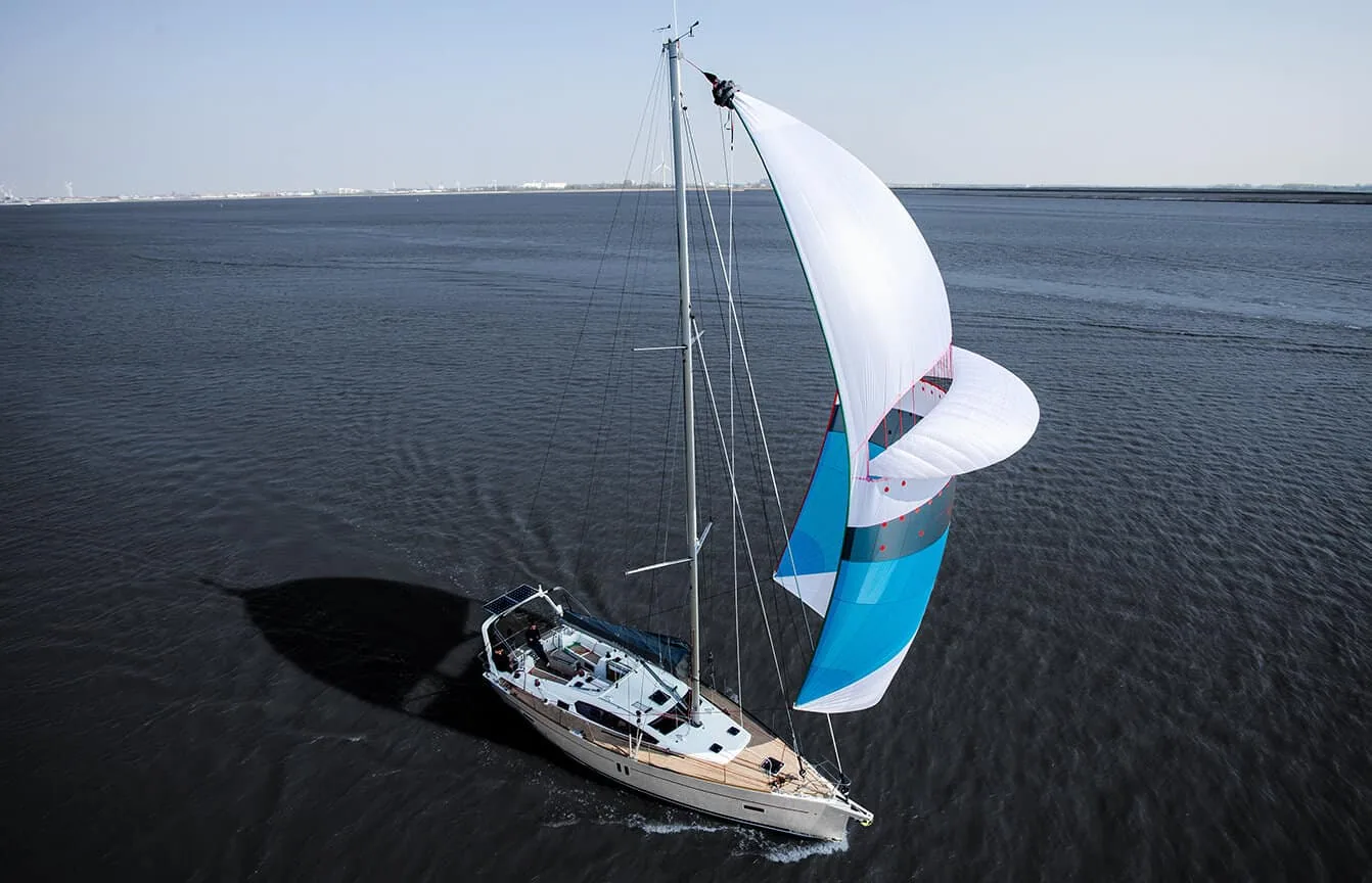 Aerial view of a cruising yacht flying a white and blue asymmetric spinnaker