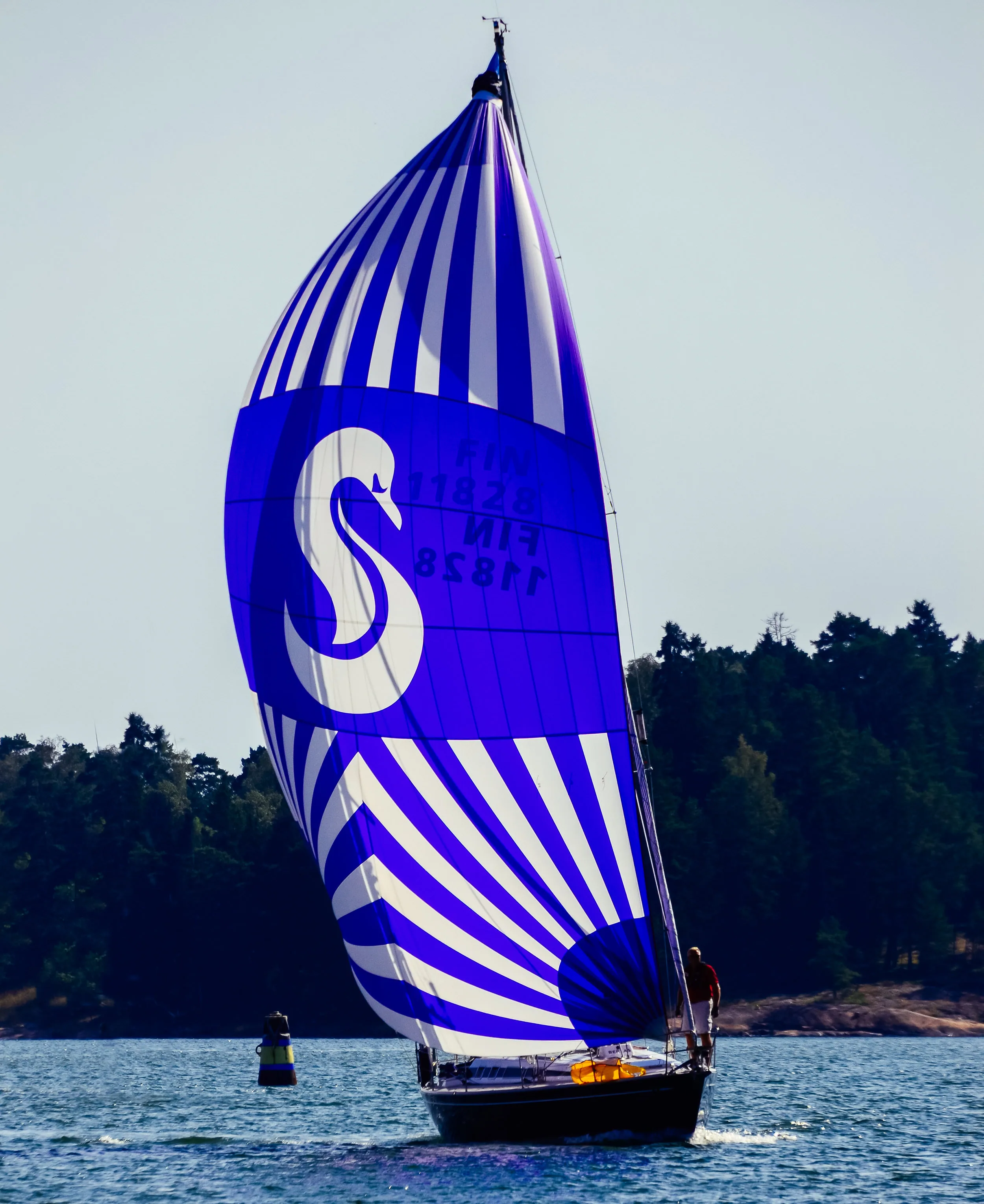 Swan yacht flying a blue and white striped spinnaker with the Swan 'S' emblem
