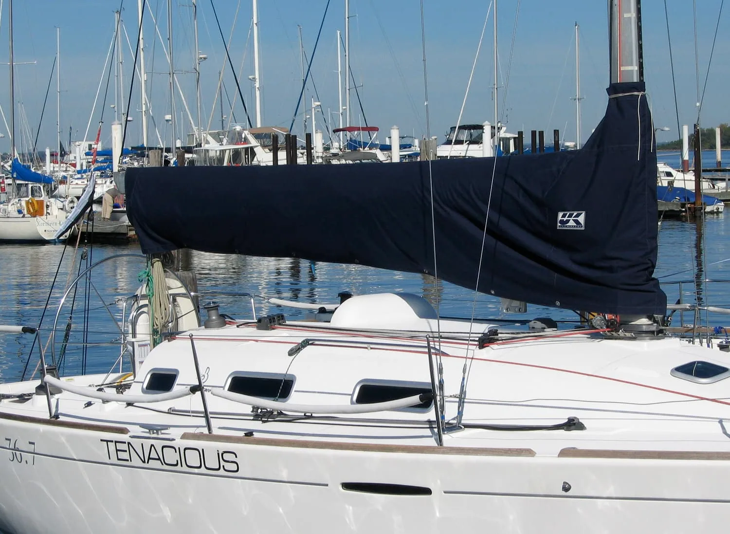 Navy blue UK Sailmakers sail cover on the boom of the sailboat Tenacious in a marina