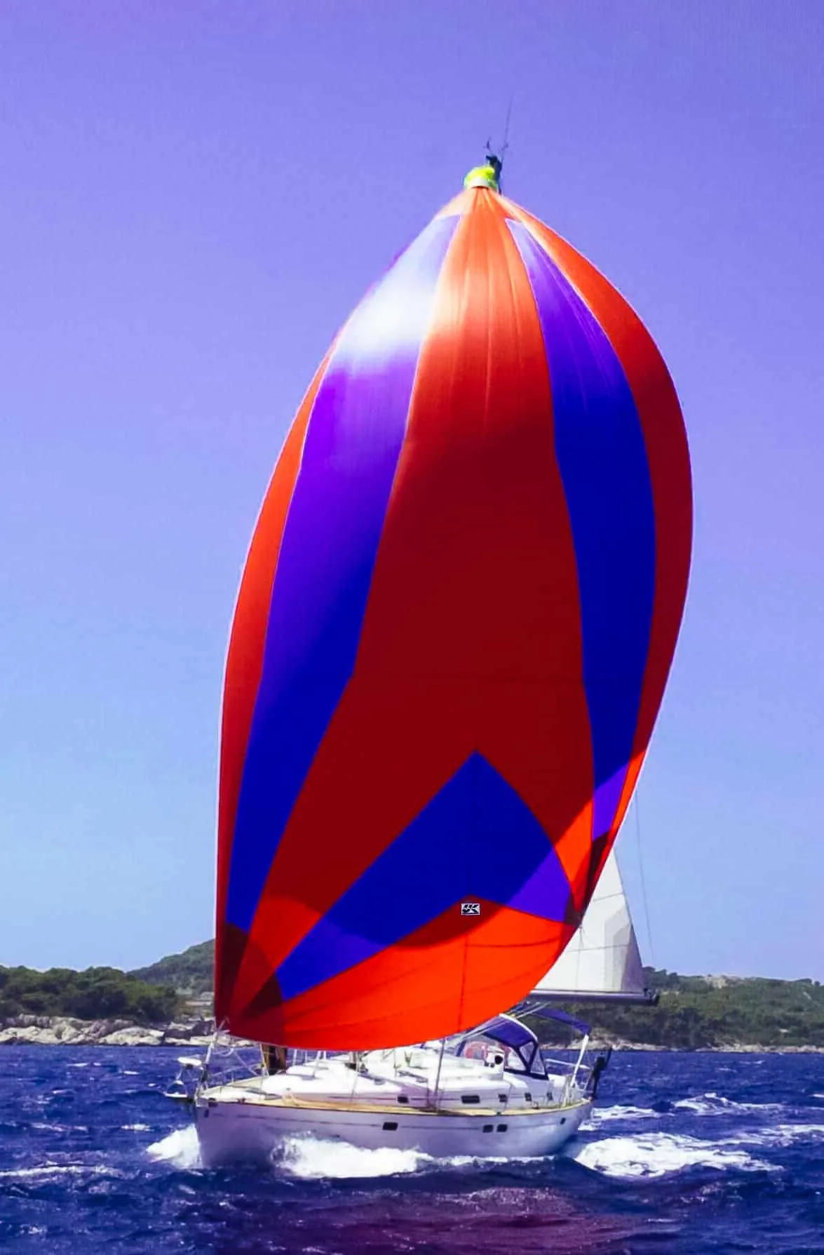 Beneteau cruiser flying a red, purple and blue asymmetric cruising spinnaker