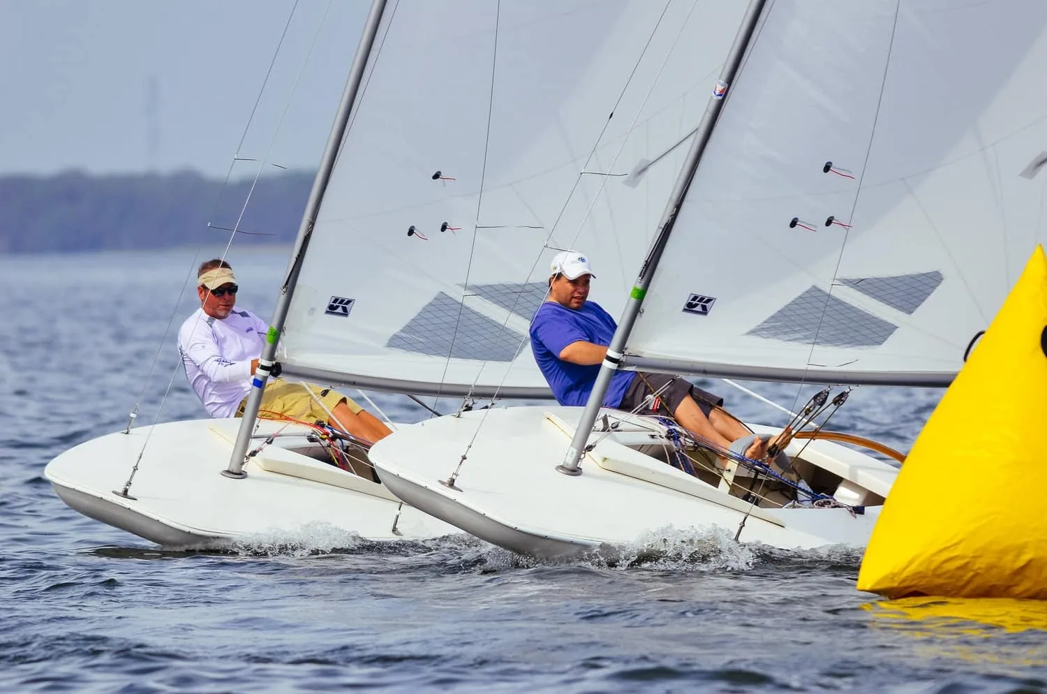 Two MC Scows racing close together as they round a yellow mark