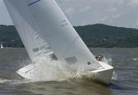 Soling heeled over hard with its bow plunging into a wave
