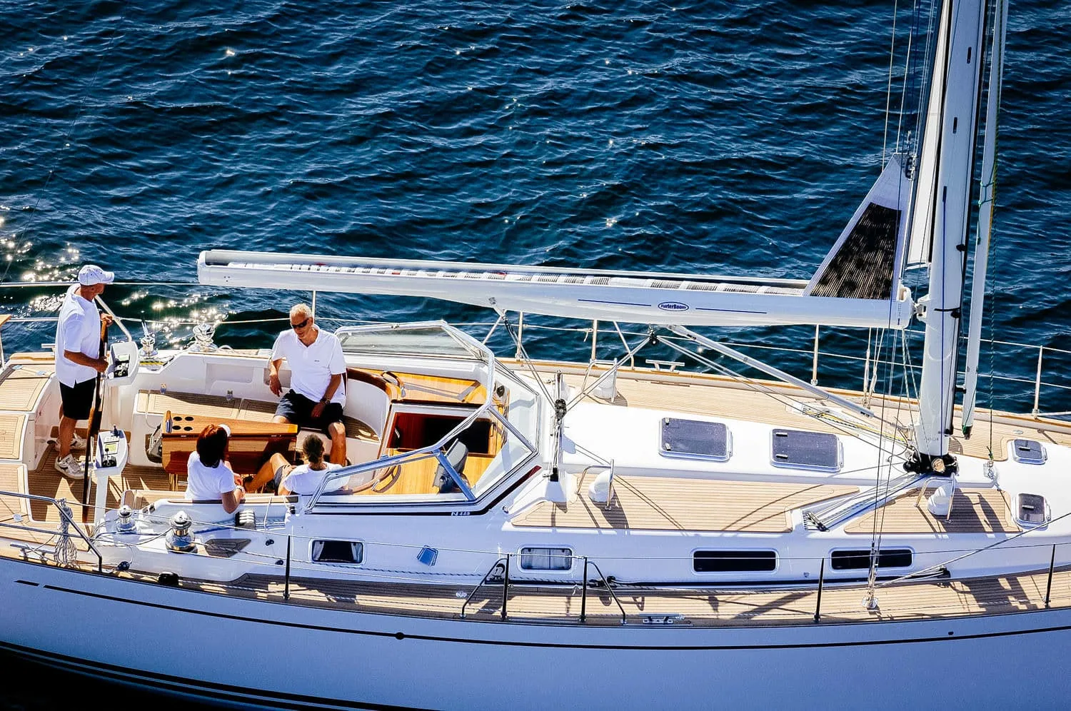 Crew on deck beside an oversized in-boom furling boom and mast base