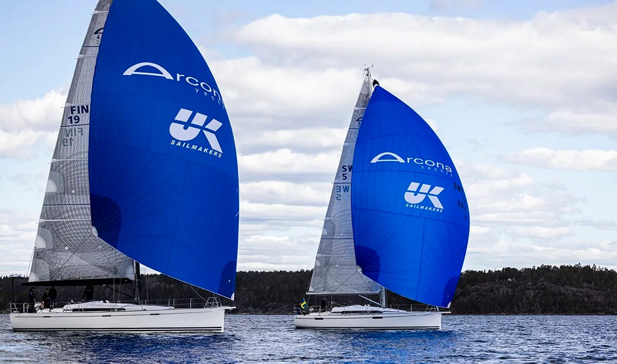 Two Arcona yachts running downwind under blue spinnakers printed with the UK Sailmakers logo