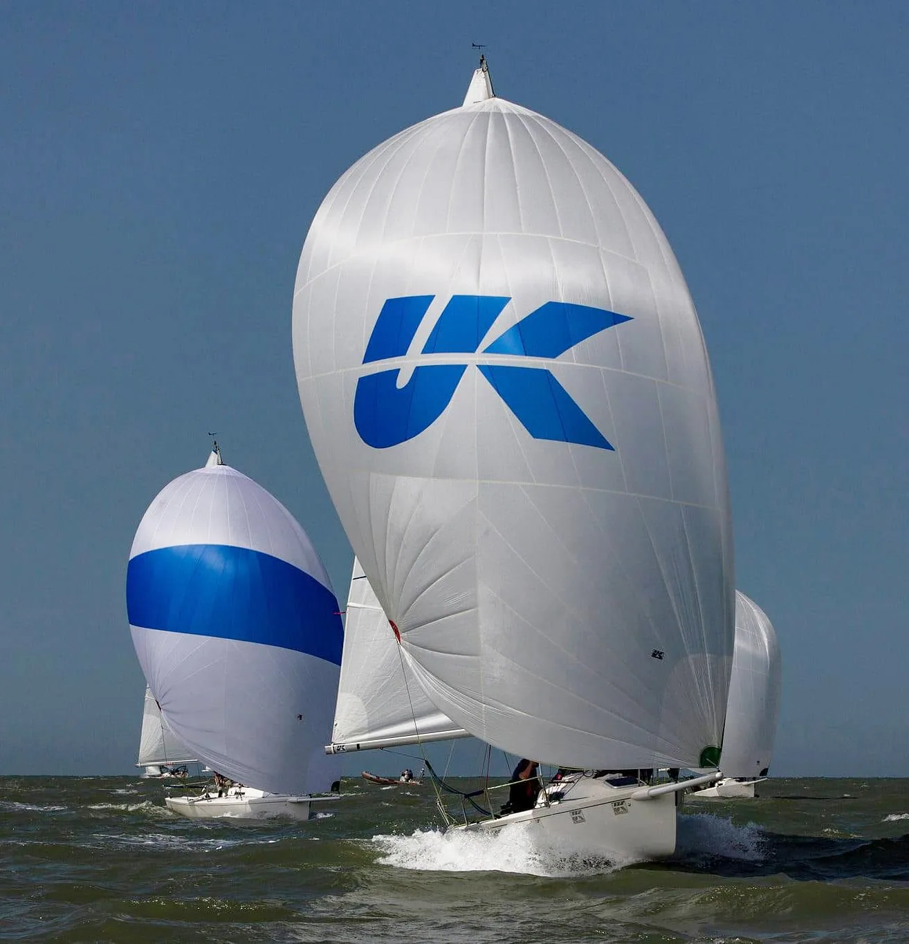 J/80 sailboats racing under spinnakers printed with the UK Sailmakers logo