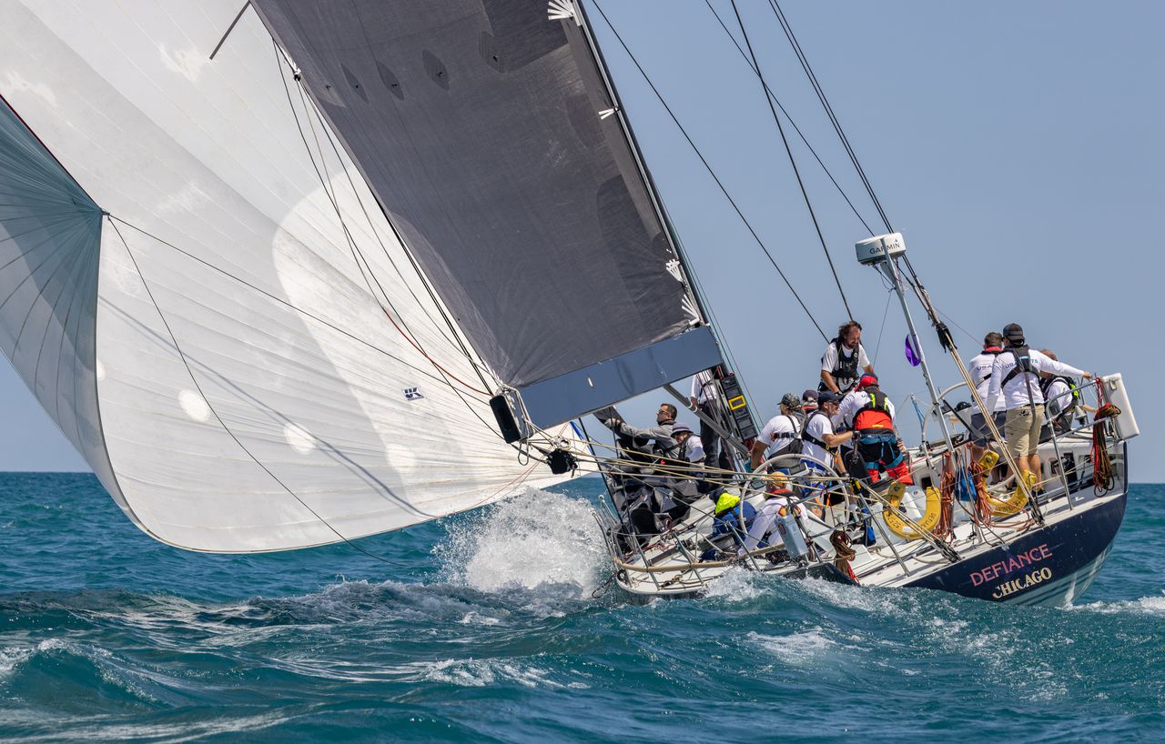 Racing yacht Defiance of Chicago heeled hard with a large crew and spinnaker set