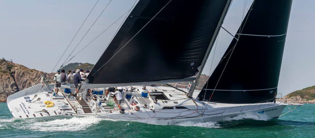 JELIK, a Reichel/Pugh 77, racing under black Uni-Titanium sails near a rocky coast