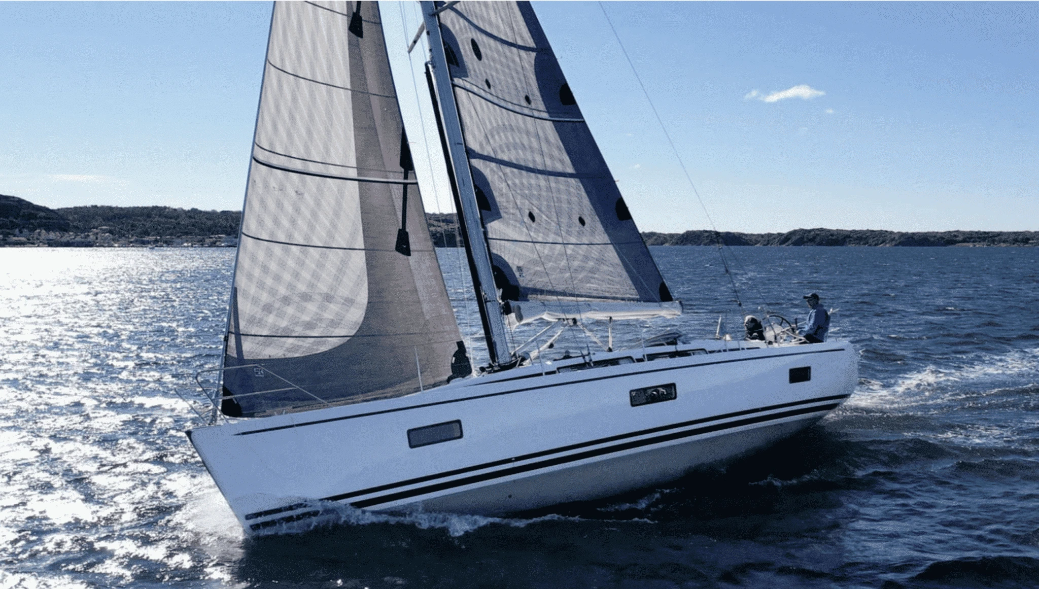 Linjett 39 sailing close-hauled under grey X-Drive® mainsail and jib, coastal hills behind