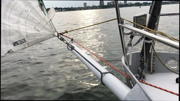 Sail tack shackled to the end of the bowsprit during a spinnaker peel, red line running aft