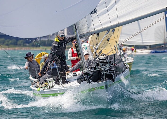 Fleet of racing keelboats jockeying for position with crew hiking out