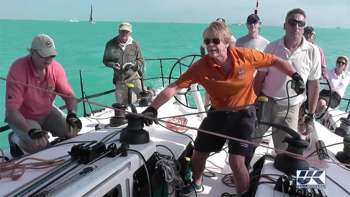 Crew tailing a line at the mast winches during a regatta in turquoise water