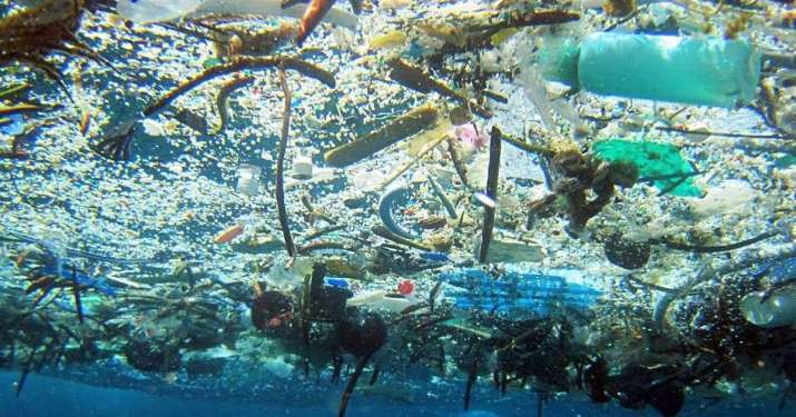 Plastic debris and bottles floating at the ocean surface, seen underwater