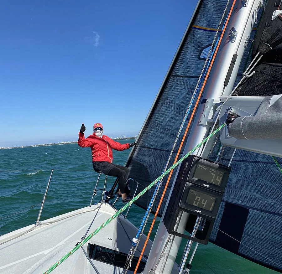 Crew member perched on the bow rail of Italia 9.98 Relentless III underway