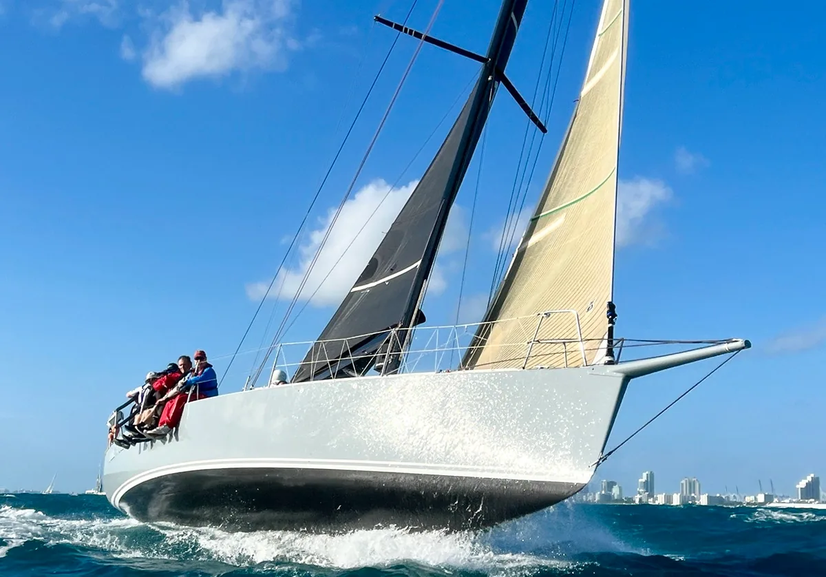 J/122 Dire Wolf heeled hard on a bow-on approach, crew hiking to windward