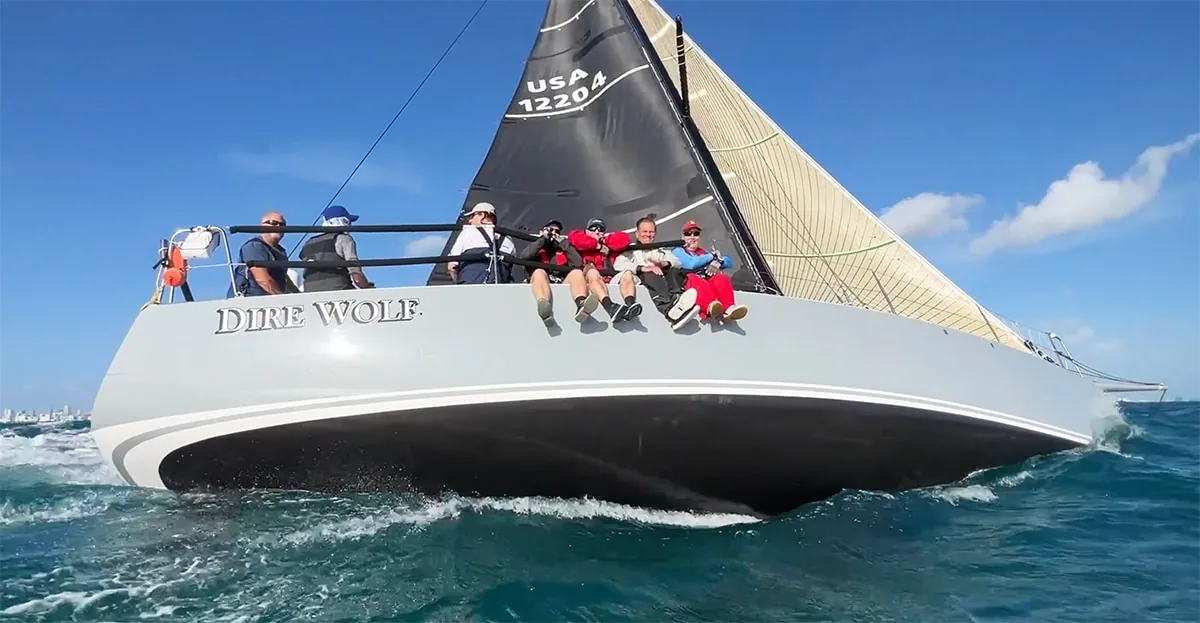 J/122 Dire Wolf racing with crew hiking, boat name visible on the hull
