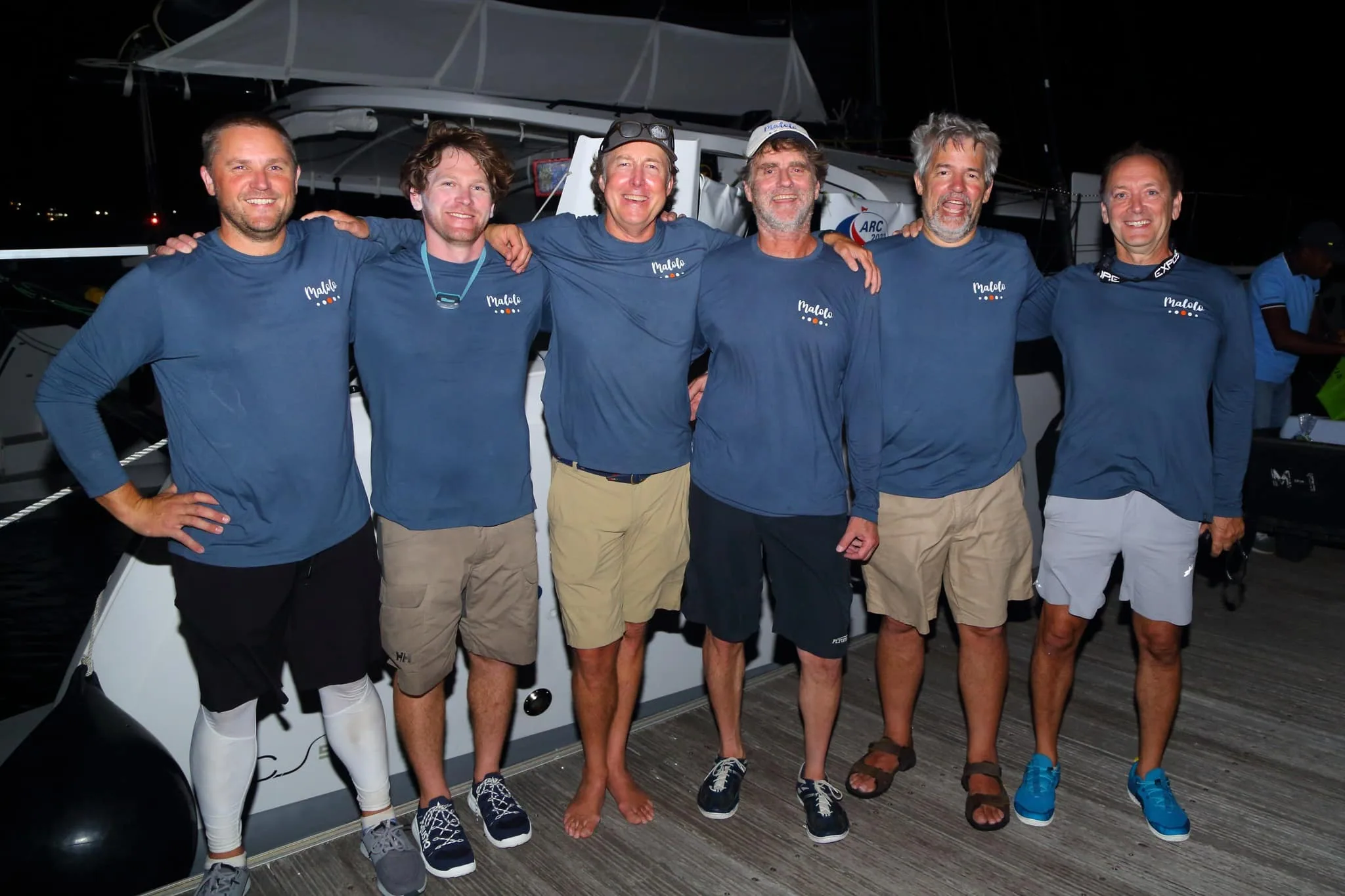 Malolo's crew posing together on deck at night in matching Malolo shirts