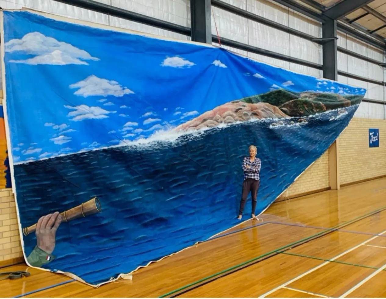 Large recycled sail painted as an ocean scene, hung inside a hall for scale