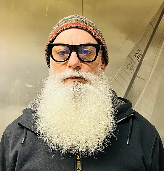 John McMahn, bearded and bespectacled, in front of a sail graphic backdrop