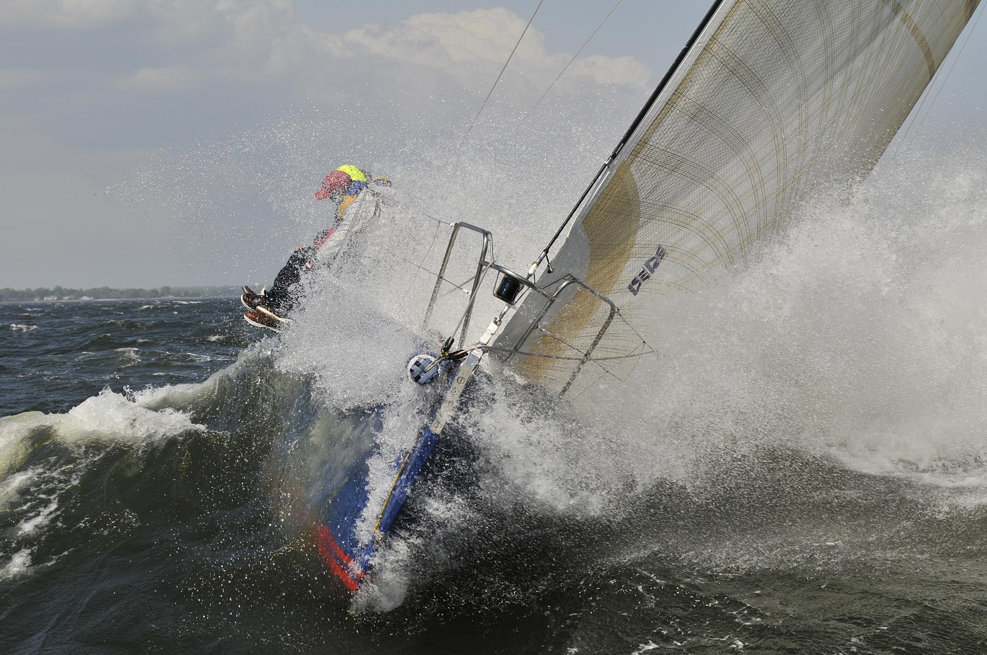 J/133 buries her bow through a breaking wave crest in heavy weather