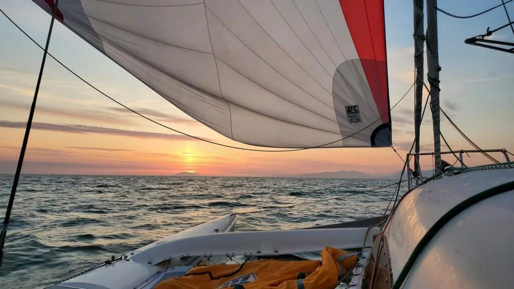 Geneva sails at sunset under her UK Sailmakers spinnaker during the R2AK