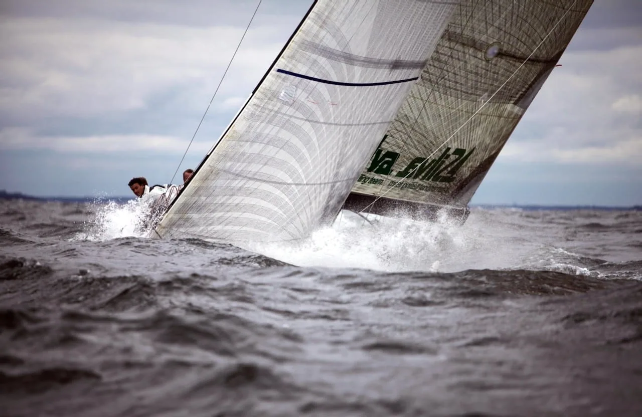 Sailboat crashing to windward through steep waves, closehauled under a full mainsail