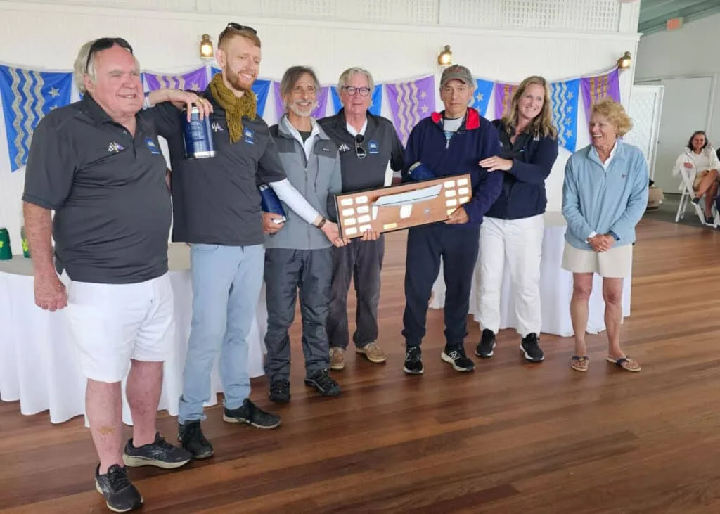 Winners of the Robie Pierce One-Design Regatta pose indoors holding an award plaque