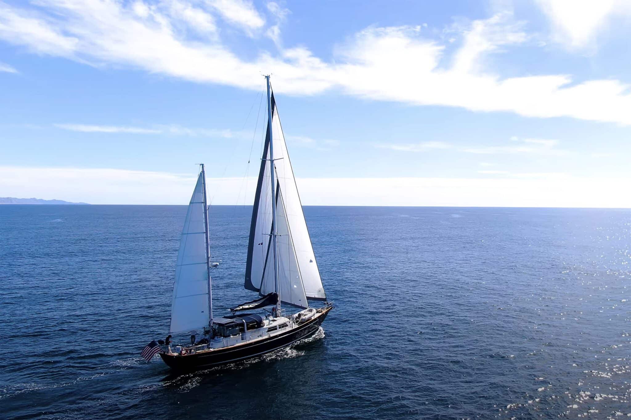 Ketch-rigged sailboat RESILIENCE underway on open water with a US flag flying