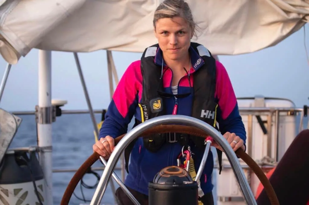Portrait of a woman at the wheel wearing a life jacket during offshore sailing
