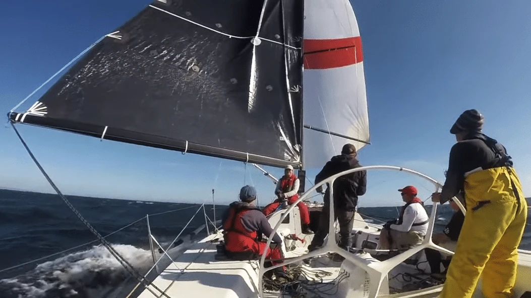 Crew working the foredeck under a dark and white spinnaker in choppy conditions
