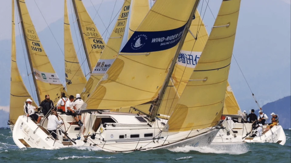 Fleet of boats flying yellow spinnakers overlapped at a close mark rounding