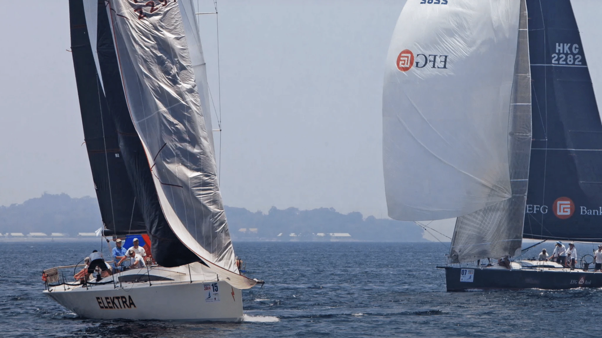 Two boats sailing downwind close together, one with a collapsing grey asymmetric spinnaker