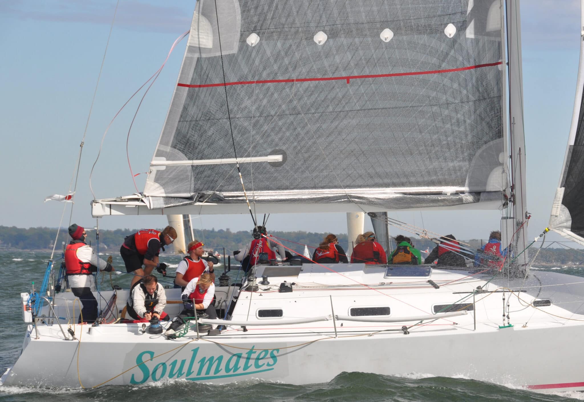 Racing sloop Soulmates sailing upwind with a full crew on the rail
