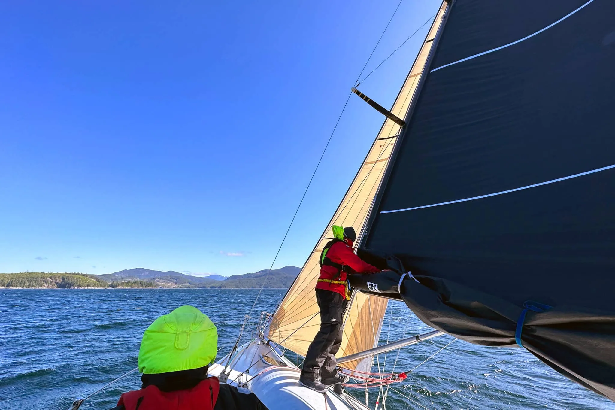 Crew aboard Jackrabbit reefing a UK Sailmakers Titanium mainsail on open water