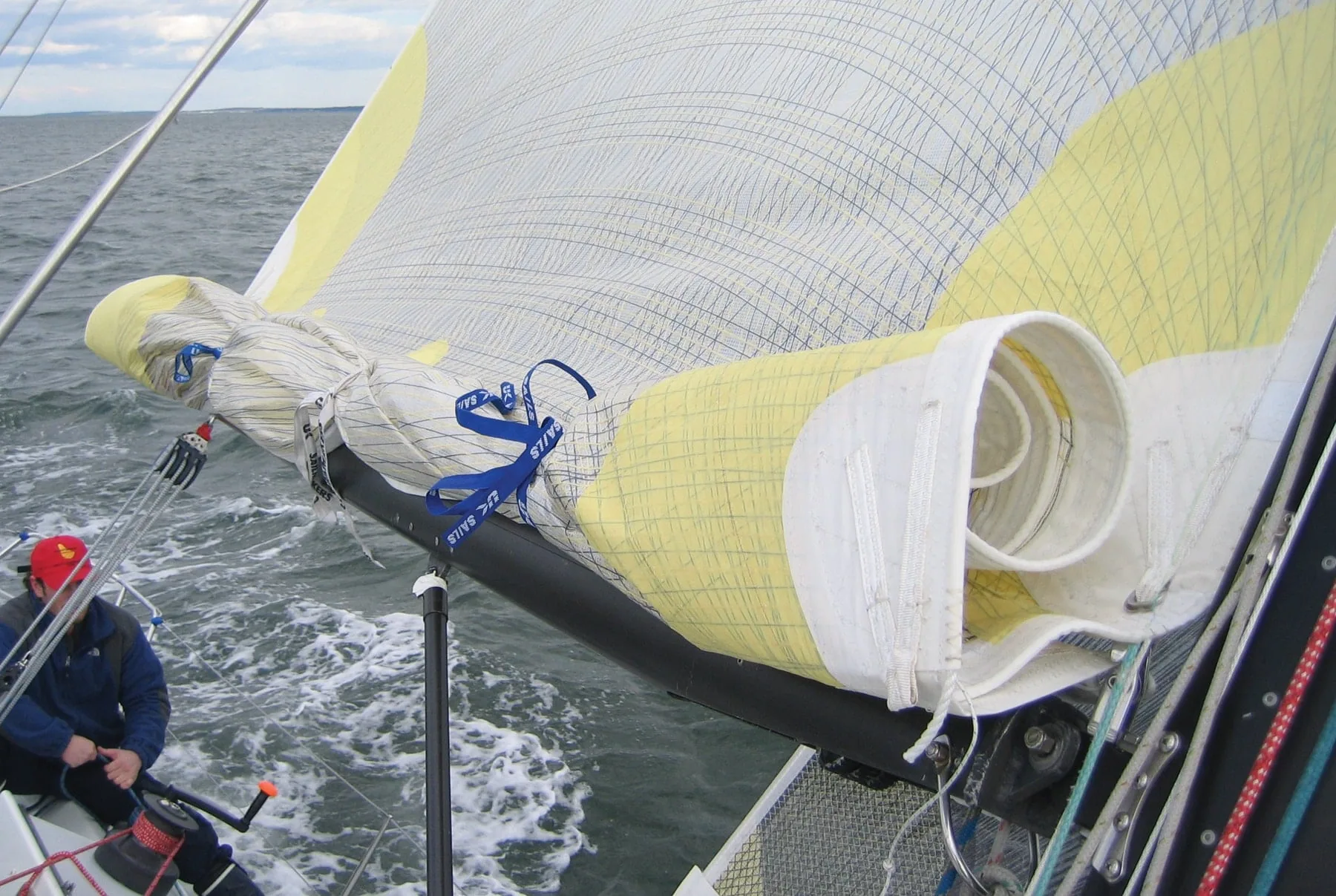 Reefed mainsail's loose fold bundled to the boom with blue sail ties