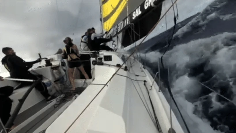 Crew scrambling on the foredeck as a spinnaker takedown goes wrong in rough water