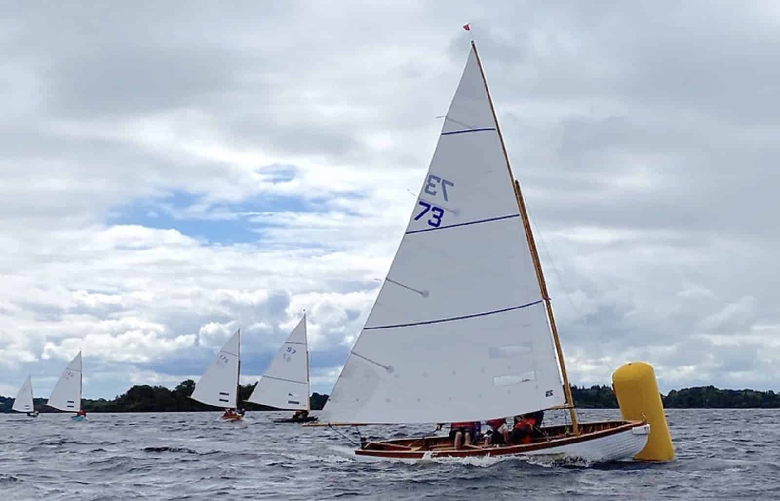 Classic gaff-rigged Shannon One Design dinghy sailing past a yellow racing mark