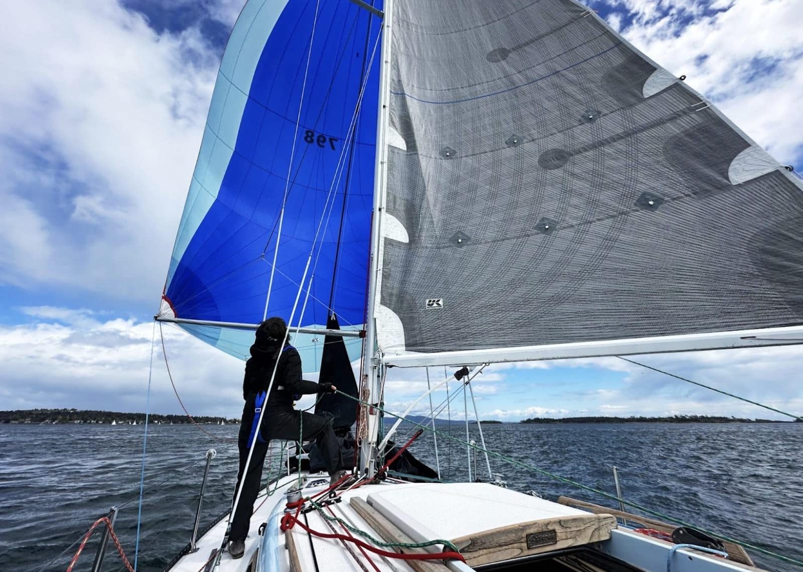 Sailor at the helm reaching past coastal islands under mainsail and jib