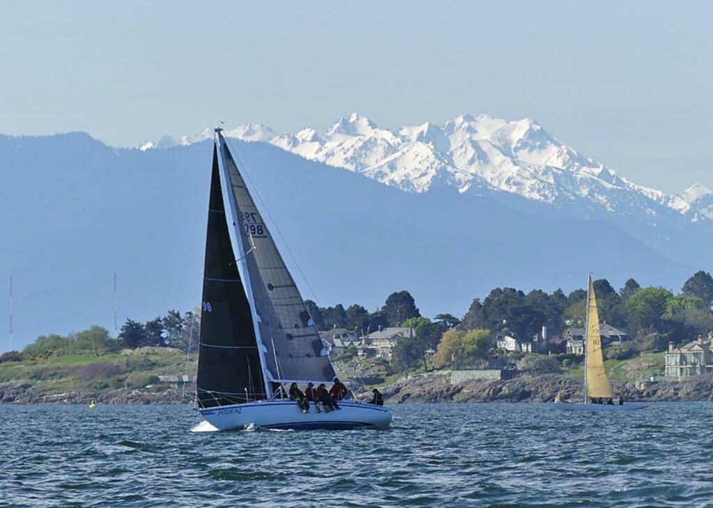 PITORAQ racing under dark sails with snow-capped mountains in the background