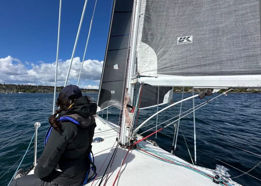 PITORAQ's crew reaching hard under dark sails marked with the UK Sailmakers logo