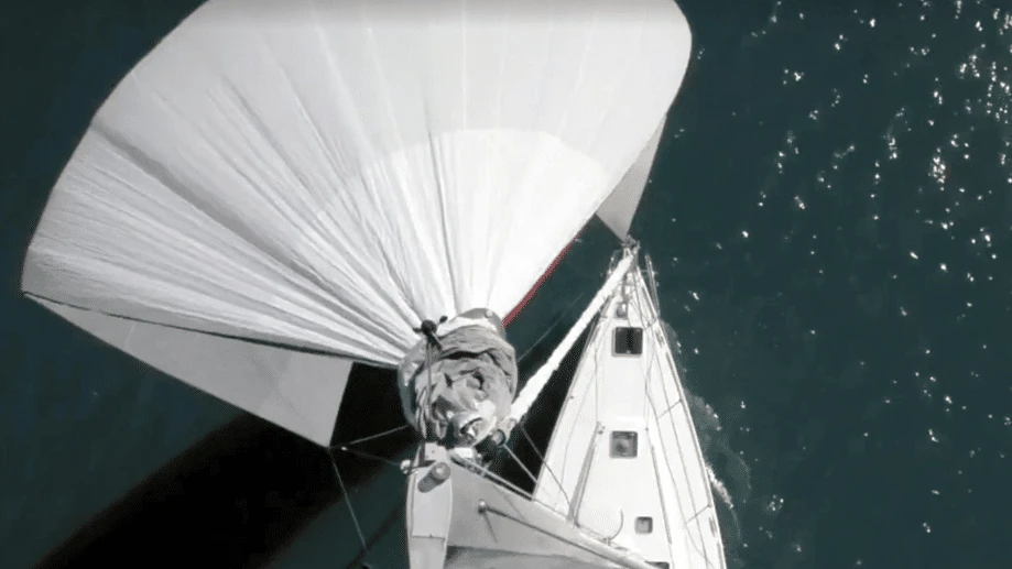 Overhead view of a spinnaker being gathered into its sock during a douse