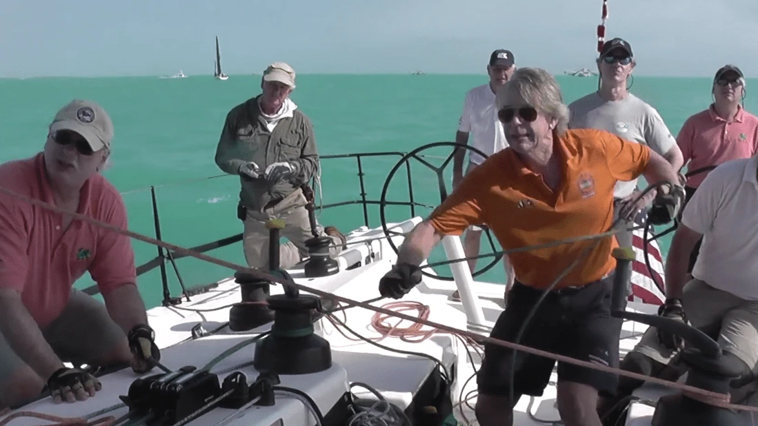 Crew working the pit and mast winches during a regatta in turquoise water