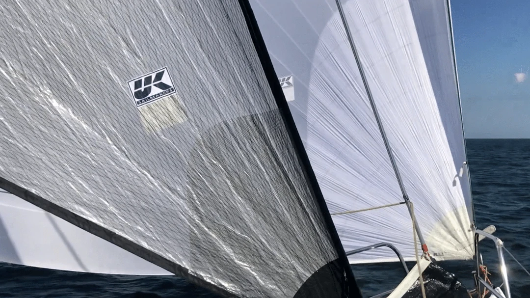 UK Sailmakers logo tag on a grey mainsail beside a white staysail set forward